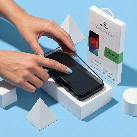 Mains plaçant un protecteur d'écran Solidenz sur un smartphone noir. Emballage à côté du téléphone.