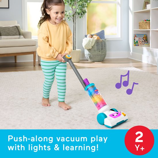 Meisje duwt een vrolijke, felgekleurde speelgoedstofzuiger met een gezichtje en lichtjes.