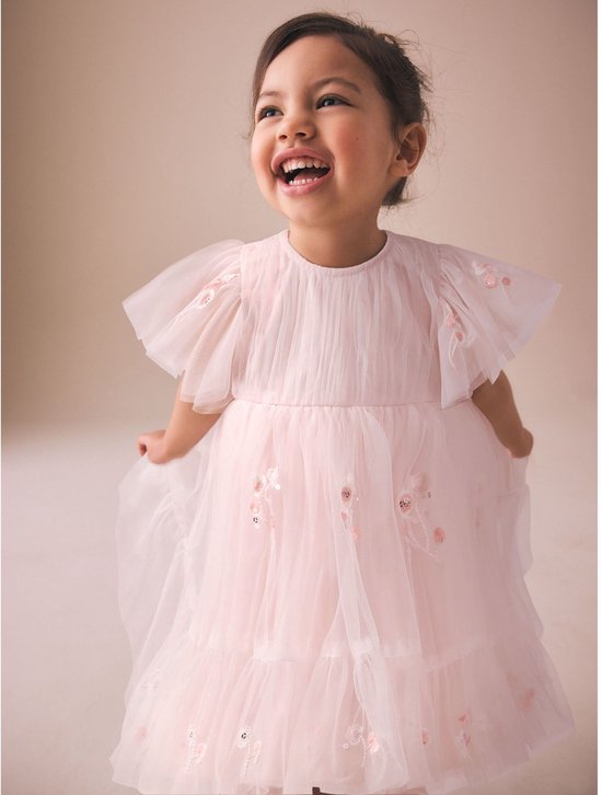 Meisje in een roze, off-shoulder mesh feestjurk met korte mouwen, bloemen-appliques en ruches, lachend.