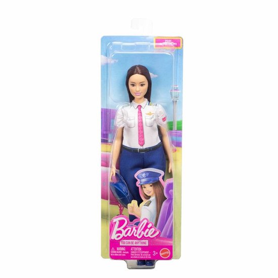 Barbie pop als piloot met een wit uniform, blauwe broek en roze stropdas. Houdt een blauwe pet vast.