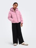 Meisje in roze pufferjack met capuchon en zwarte broek.