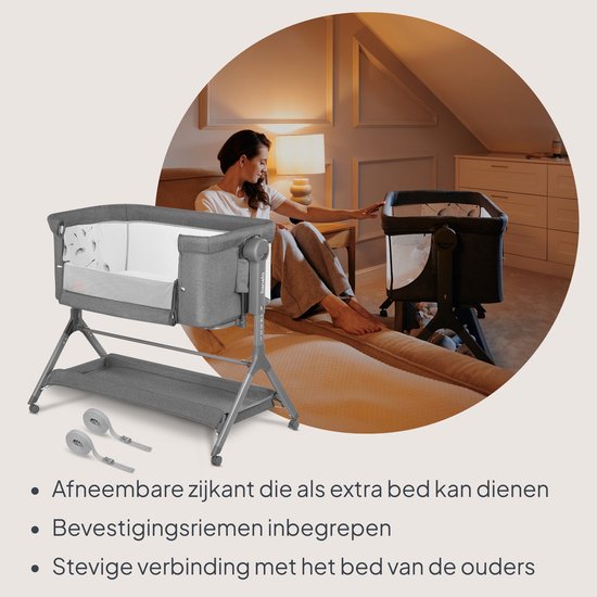 Grijze co-sleeper met afneembare zijkant, bevestigingsriemen en een moeder op de achtergrond.