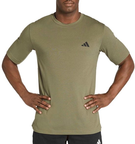 Man met handen in de zij, draagt een legergroen T-shirt met een zwart Adidas logo op de borst.