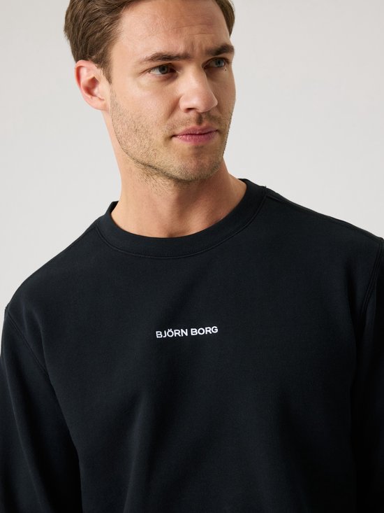 Close-up van een zwarte sweater met 'BJORG BORG' in witte letters op de borst.