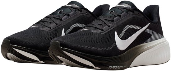 Paar zwarte Nike hardloopschoenen met witte Swooshes en witte zool, vanuit een hoek gezien.
