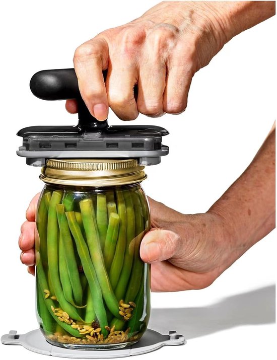 Grijze potopener met zwarte handgreep die wordt gebruikt om een pot augurken te openen.