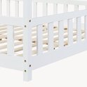 Détail des barreaux blancs en bois et du sommier à lattes d'un lit maison.