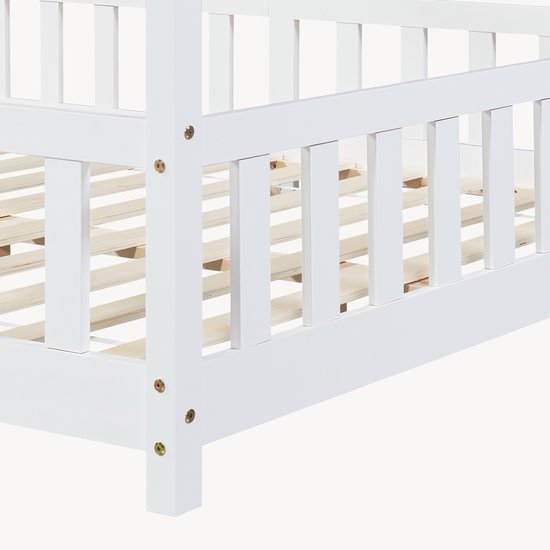 Détail des barreaux blancs en bois et du sommier à lattes d'un lit maison.