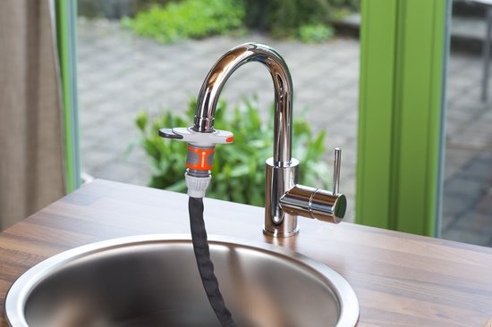 Zilverkleurige kraan met zwarte slang met oranje connector in een gootsteen.