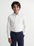 Garçon en chemise blanche à manches longues et pantalon bleu marine.