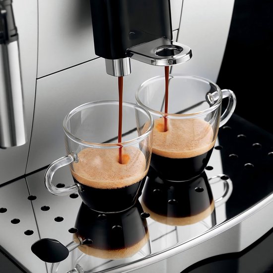 Zwarte espresso wordt in twee glazen mokken geschonken uit de zilveren De'Longhi Magnifica S espressomachine.