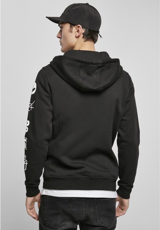 Man met pet, draagt de achterkant van een zwarte hoodie met ritssluiting.