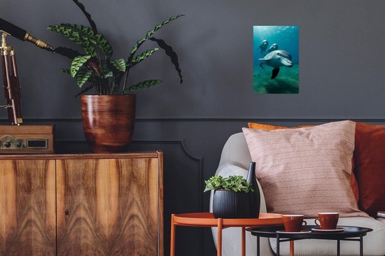 Trois dauphins nagent sous l'eau dans une eau bleue avec des rayons de soleil, accrochés à un mur dans un salon.
