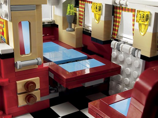 Interieur van een rode LEGO camperbus met keukentje, wastafel met gouden kraan en geblokte vloer.