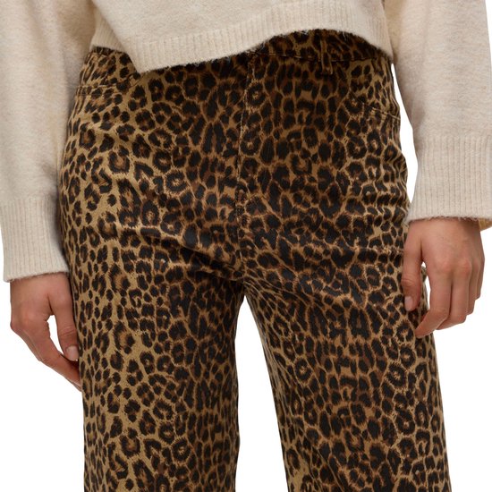 Model draagt een beige trui en een spijkerbroek met luipaardprint, hoge taille.