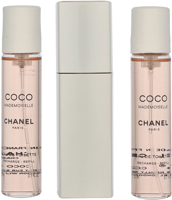 Drie flacons Coco Mademoiselle Eau de Toilette van Chanel met gouden dopjes, naast een zilverkleurige verstuiver.