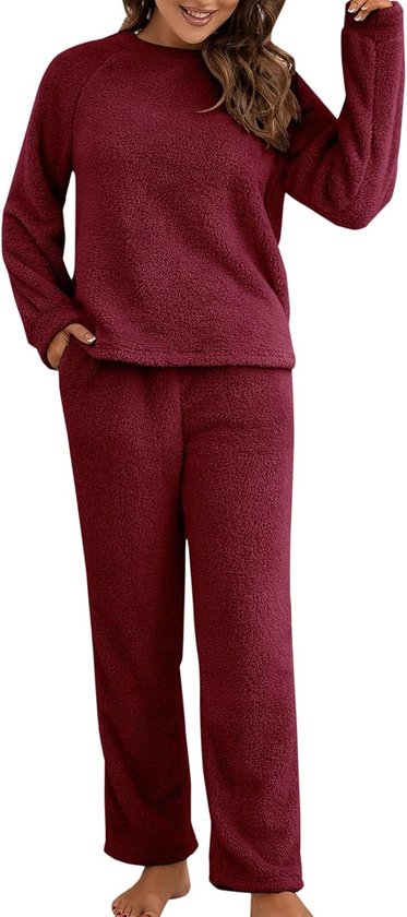 Een vrouw staat rechtop in een bordeauxrode, pluizige pyjama met lange mouwen en broek.