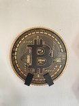 Gouden en zwarte Bitcoin-medaille met "BITCOIN DECENTRALIZED PEER TO PEER" tekst.