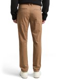 Achterkant van een man in bruine chino met instoppend shirt, en witte schoenen.