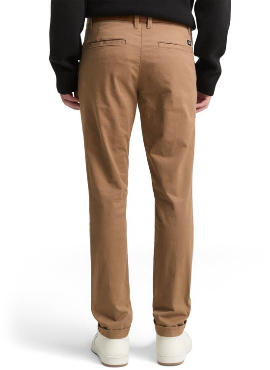 Achterkant van een man in bruine chino met instoppend shirt, en witte schoenen.
