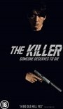 Een man in een zwart T-shirt met de tekst 'THE KILLER' en 'SOMEONE DESERVES TO DIE'. Hij houdt een pistool met demper vast. Leeftijdsclassificatie 16.
