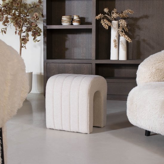 Taupe poef met verticale ribbels in een woonkamer.