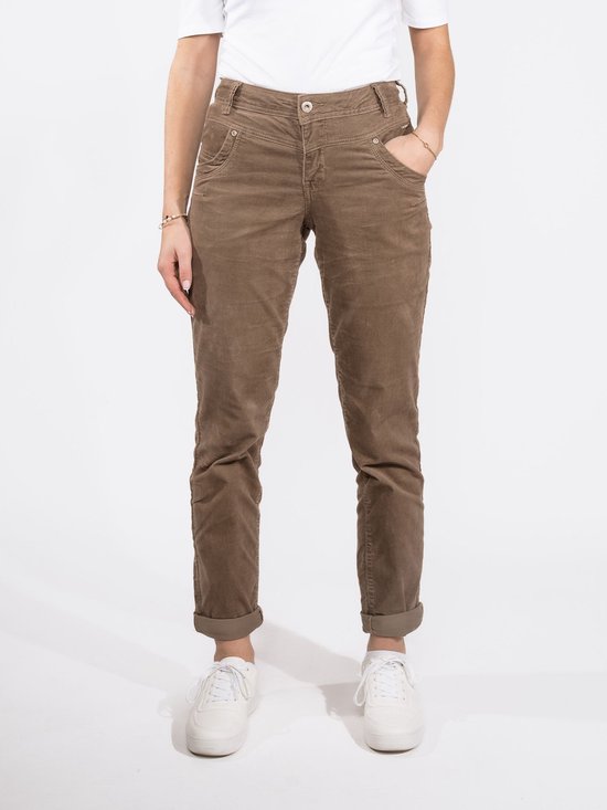 Bruine corduroy broek met opgerolde broekspijpen, gedragen door een model met witte sneakers.