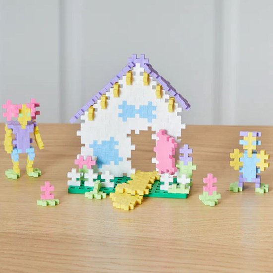 Pastel Plus-Plus bouwset met een huisje, twee figuurtjes en bloemen in paars, geel, wit, groen en blauw.