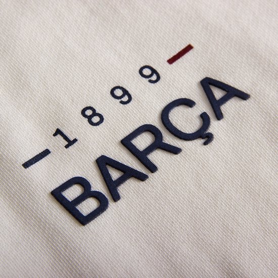 Detail van een ecru sweater met de tekst '-1899- BARÇA' in marineblauwe letters.