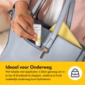 Een hand met een tube Purelan Lanolin cream wordt in een blauwgrijze handtas gestoken.