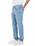 Homme portant un jean Replay bleu clair, vue de côté, avec logo sur la poche arrière.