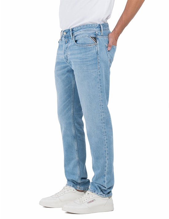Homme portant un jean Replay bleu clair, vue de côté, avec logo sur la poche arrière.