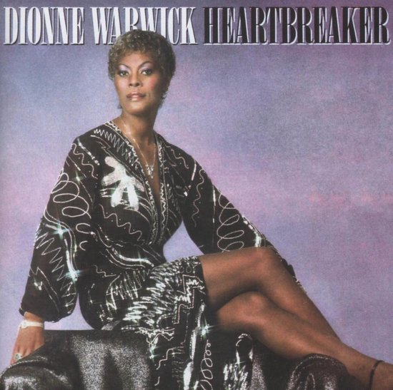 Dionne Warwick Heartbreaker albumhoes met haar zittend op een stoel, een zilverkleurige jurk met zwarte patronen.