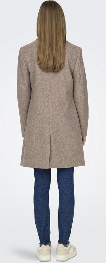 Vrouw in bruine jas, witte top en blauwe jeans, van achteren.