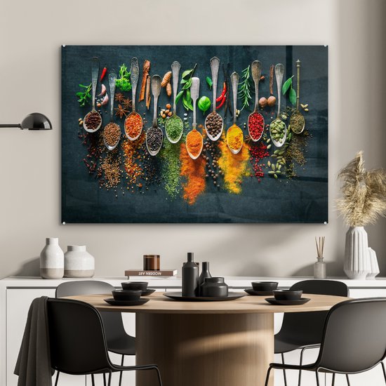 Glasschilderij met een rij zilveren lepels gevuld met kleurrijke kruiden en specerijen, hangend boven een eettafel.