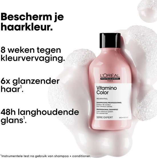 Roze fles L'Oréal Professionnel Vitamino Color shampoo met zwarte dop, omringd door witte schuimachtige bubbels.
