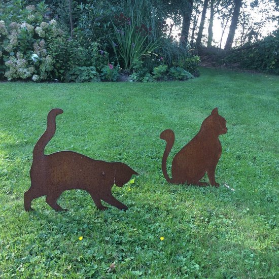 Twee roestkleurige metalen katten silhouetten in een grasveld.