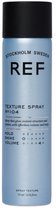 Blauwe sprayfles met zwarte dop, met de tekst 'REF STOCKHOLM SWEDEN TEXTURE SPRAY N°104'.