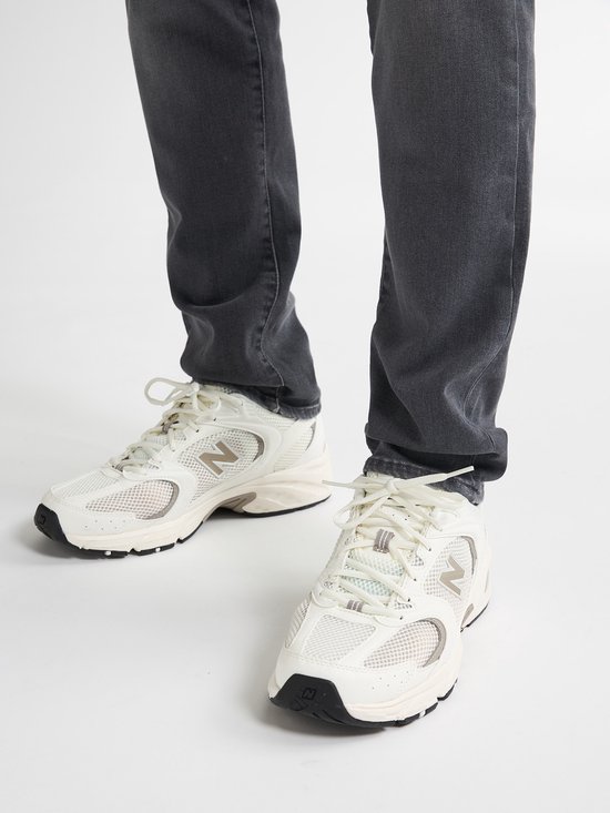 Witte lage sneakers van mesh en suède met beige accenten en een zwarte neus.