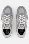Grijze Adidas sneakers met witte veters en lichtgroene strepen. De zool is wit met een zwarte rand.