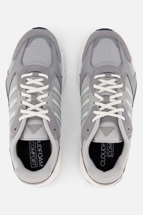 Grijze Adidas sneakers met witte veters en lichtgroene strepen. De zool is wit met een zwarte rand.