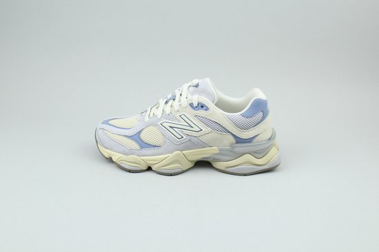 Zijkant van een beige en lichtblauwe New Balance 9060 sneaker met witte veters.
