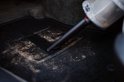 Tapis de voiture noir nettoyé sur un sol poussiéreux dans une voiture.