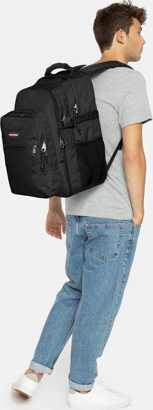 Zwarte Eastpak rugzak gedragen door een man met grijs shirt en spijkerbroek.