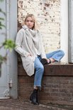 Lichtgrijs gebreid vest met grote reverskraag, openvallend model, gedragen door een blonde vrouw met spijkerbroek.