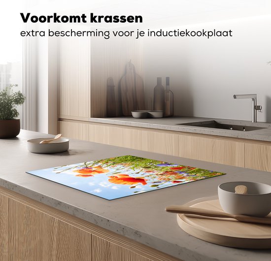 Een inductiebeschermer met een opdruk van klaprozen en korenbloemen in een veld, op een aanrecht.