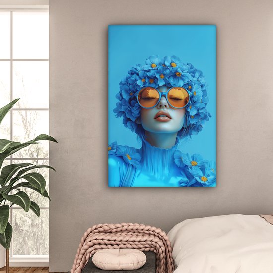 Portrait bleu d'une femme avec des lunettes orange et des fleurs, dans une chambre près d'une fenêtre.