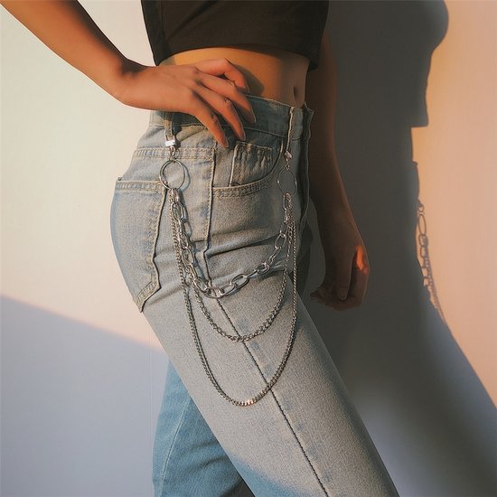 Zilverkleurige pantalonketting met drie lagen schakels, gedragen aan een spijkerbroek.