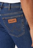 Close-up van de achterzak van een donkerblauwe Wrangler jeans met bruin lederen label.