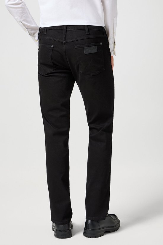 Man van achteren gezien, met een zwarte Wrangler jeans met rechte pijpen.